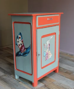 Petit meuble bas fermé de 3/4, après rénovation, avec illustrations peintes à la main sur deux faces, sur le thème Alice au pays des merveilles